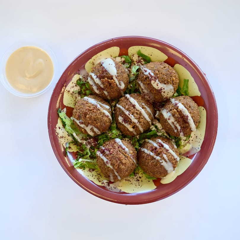 Shawarma Way's falafel plate with seven falafel balls, lettuce, tomatoes, and tahini sauce.
