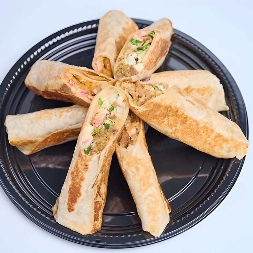 A black platter filled with several Shawarma Way wraps, some cut to show the meat and vegetables.